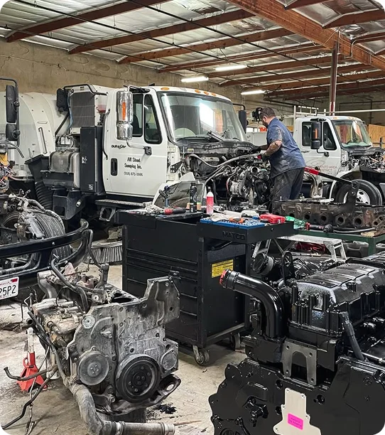 Heavy-duty truck engine repair shop with technicians servicing diesel engines and commercial trucks