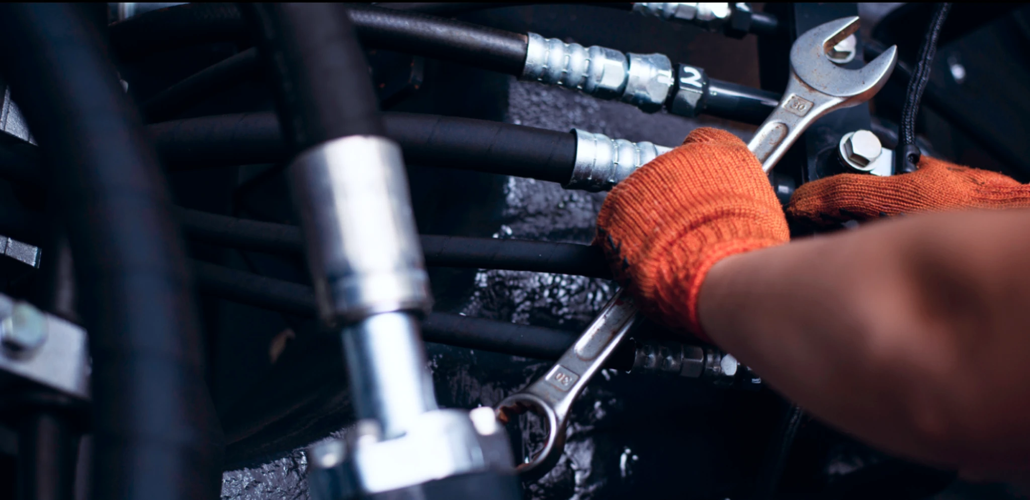 Technician repairing hydraulic system with wrench